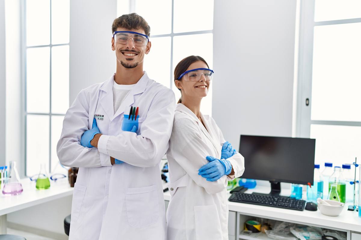 Lab team wearing scientist uniform standing with arms crossed gesture at laboratory