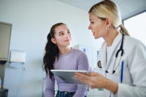 doctor explaining diagnosis to teenage girl in her office